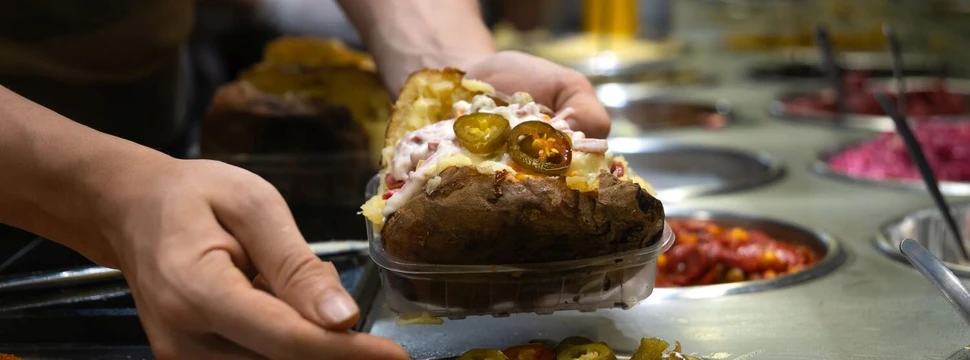 Eine Kumpir wird mit frischen Zutaten belegt