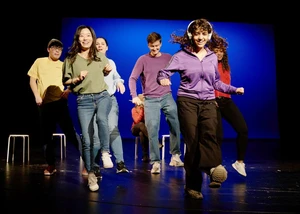 Jugendliche in bunten Pullovern tanzen auf einer Bühne