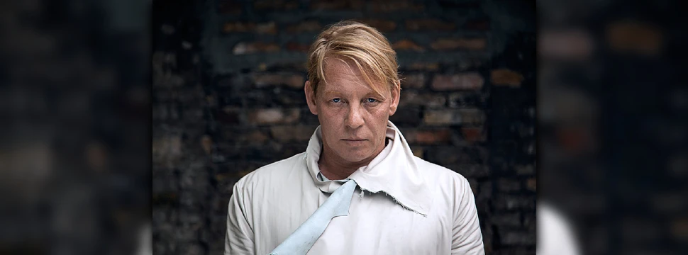 Ben Becker vor einer Steinmauer