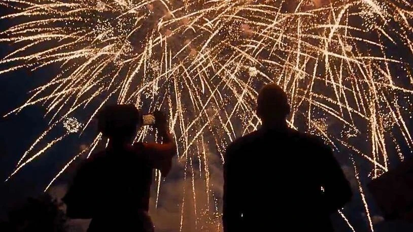 schwarze Umrisse von zwei Personen vor einem Feuerwerk am Himmel