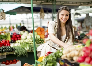 eine junge Frau kauft auf einem Wochenmarkt ein