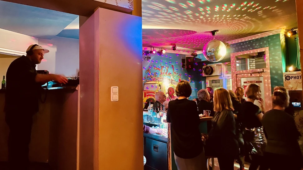 Menschen in einem Partyraum mit Diskokugel.