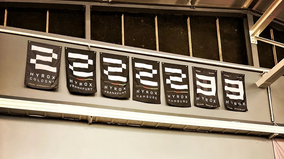 schwarze HYROX Flaggen mit den Zahlen zwei und drei hängen an einer Wand