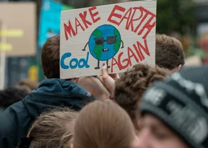 Klimaschutzplakat Klimaprotest-Schild mit der Aufschrift "Make Earth Cool Again" und einer gemalten Erdkugel mit Sonnenbrille wird bei einer Klimademonstration in die Höhe gehalten