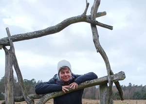 Frau steht zwischen aufgebauten Ästen in einer Waldkulisse