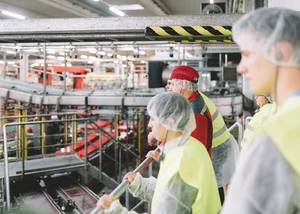 Besucher in Schutzkleidung stehen in einer Industrianlage