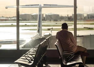 Ein Passagier an einem Flughafen, der aus dem Fenster des Gates schaut