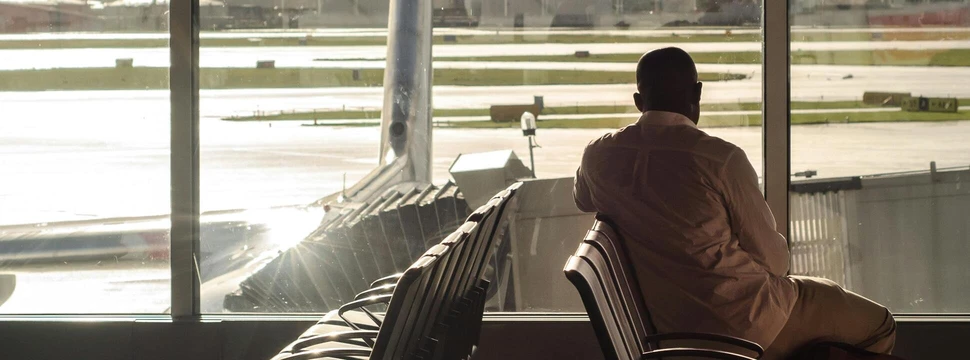 Ein Passagier an einem Flughafen, der aus dem Fenster des Gates schaut