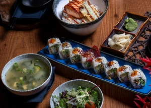 Schalen mit Salat, Suppe und Sushi auf einem Holztisch