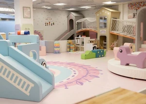 Eine liebevoll gestaltete Spielwelt mit hellen Farben, altersgerechten Spielbereichen und interaktiven Elementen.