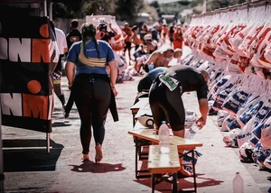 Athleten und Athletinnen in der Wechselzone vom Ironman, daneben hängen die Beutel