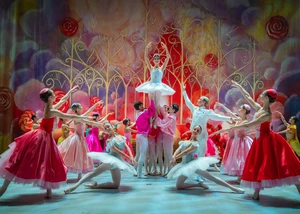 Mehrere Balletttänzer tanzen auf einer bunten und imposanten Bühne.