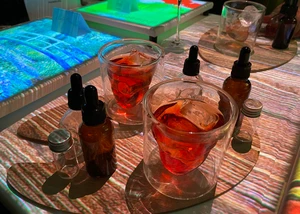 Tisch mit zwei Gläsern, kleinen Fläschchen und bunten Projektionen