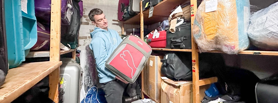 Ein Mann wuchtet einen schweren Koffer aus dem Regal
