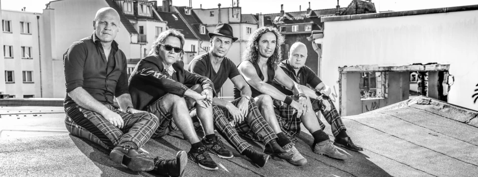 schwarz-weiß Foto von fünf Band-Mitgliedern auf einem Hausdach