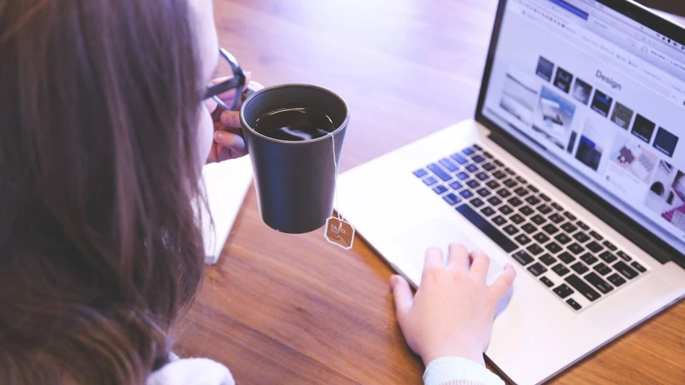 Mit einer guten Bewerbung punktet man bei Recruitern. Junge Frau mit Teetasse sitzt am Laptop
