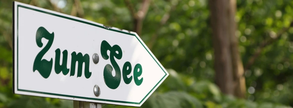 Hinweisschild welches mit der Aufschrift "Zum See" den Weg weist