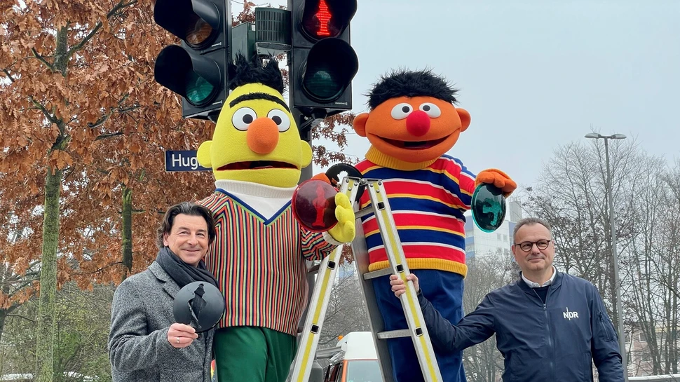 Ernie und Bert Figuren auf einer Leiter sowie zwei Männer vor einer Ampel