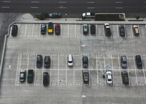 Blick von oben auf einen nummerierten Parkplatz mit diversen geparkten Autos
