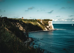 Eine Steilküste mit einem Leuchtturm im Hintergrund und der Ostsee im Vordergrund