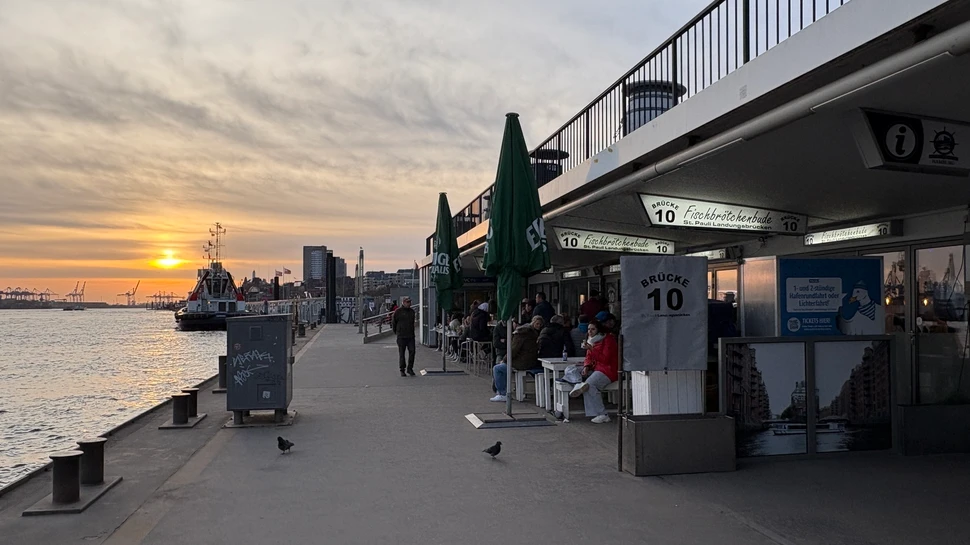 Ponton der Hamburger Landungsbrücke mit dem Imbiss Brücke 10 und der Elbe mit Sonnenuntergang im Hintergrund