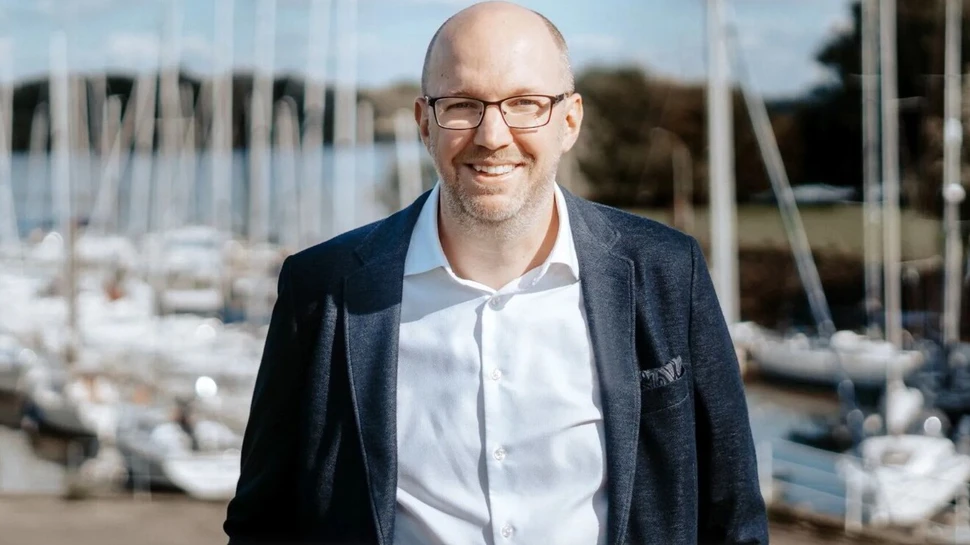 ein Mann im Anzug vor einem Yachthafen