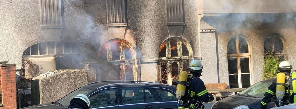 Zwei Feuerwehrmänner laufen zum brennenden Theater.