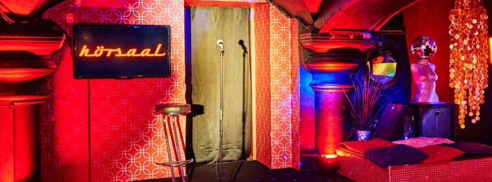 Raum im Hörsaal, bestuhlt mit Mikro auf der Bühne