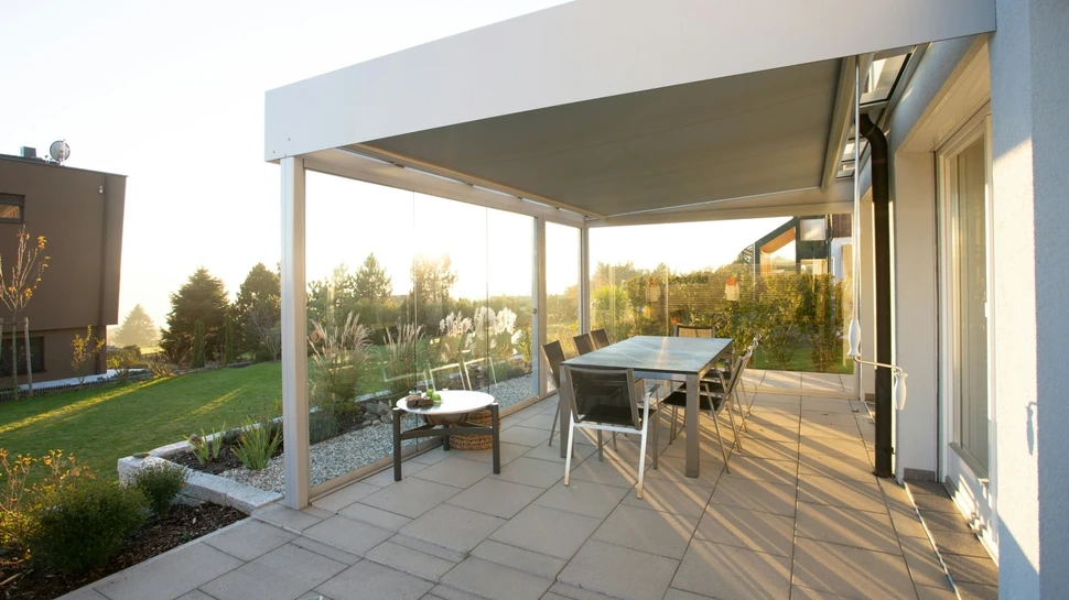 Schwarzer Metalltisch und Stühle auf überdachter Terrasse im Sonnenlicht