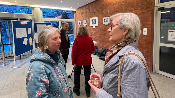 Galerie-Bild 2: Besucher der Ausstellung im Gespräch von der Wand mit den gehängten Fotos