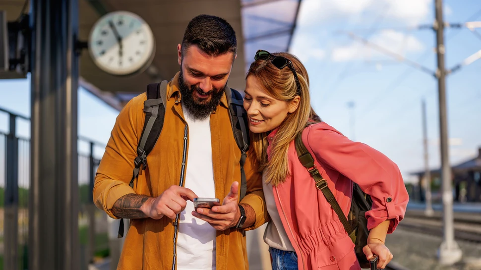 Ein Paar auf dem Bahnsteig schaut auf das Handy