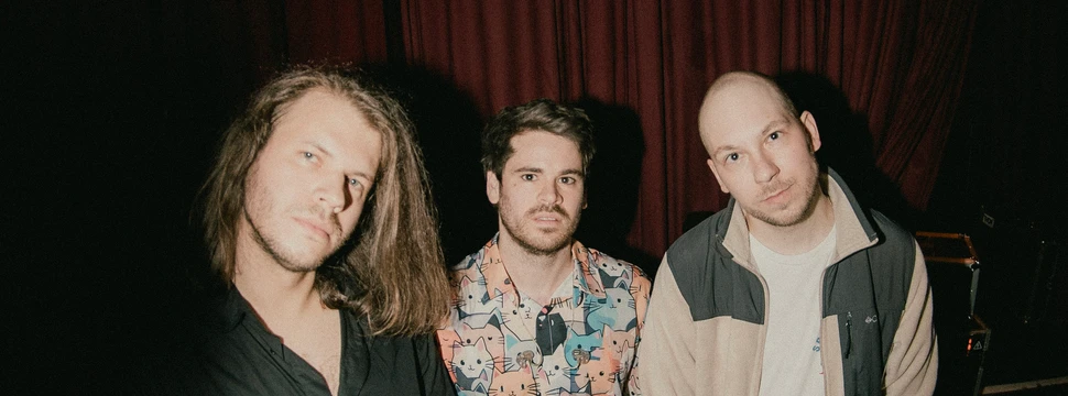 Drei Männer stehen nebeneinander und gucken in die Kamera