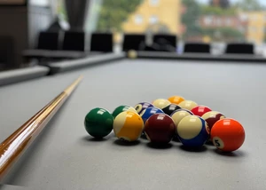 Billardtisch mit Kugeln und Queue Billard Kugeln liegen zusammen mit einem Queue auf einem Billardtisch