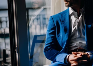 Mann mit blauem Anzug sitzt in einer Fensterbank in der Sonne