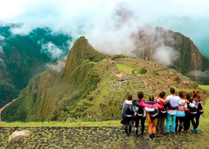 eine Gruppe von jungen Menschen steht Arm in Arm auf einem Berg in den Anden