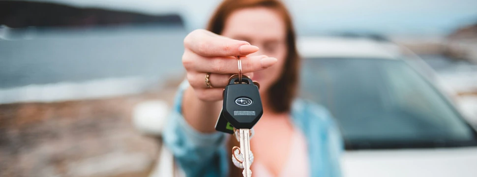 Frau präsentiert Autoschlüssel. Der Schlüssel ist im Fokus.