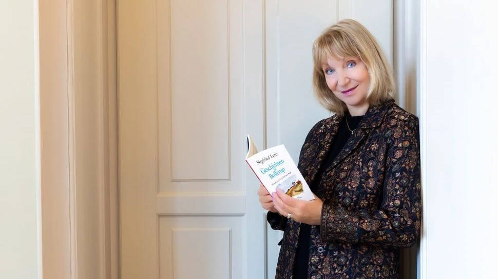 Sabine Kaack lehnt an der Wand mit einem Buch in der Hand