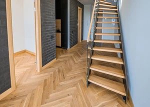 ein Flur mit Fischgrät Parkettboden und einer Holztreppe