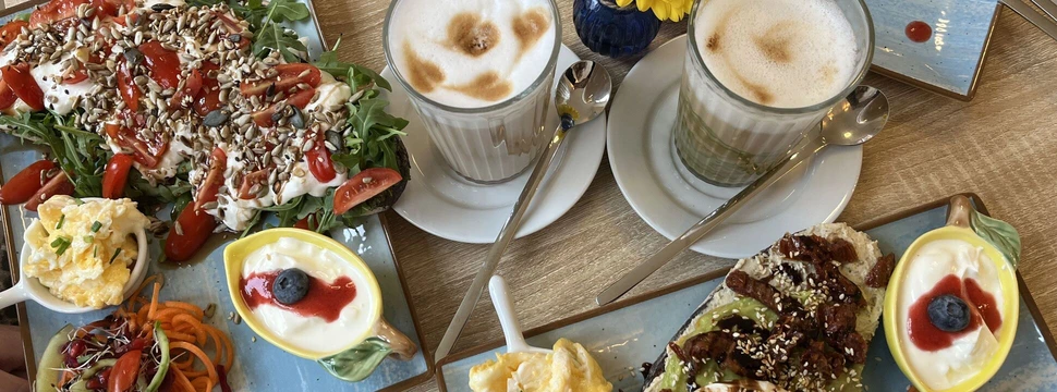 Brunch-Tisch mit zwei Stullen, Latte Macchiatos und gelbem Safran-Cupcake.