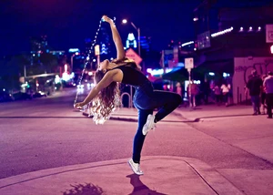 Frau tanzt Urban Dance Eine junge Frau tanzt auf der nächtlichen Straße in einer ausdrucksstarken Pose.