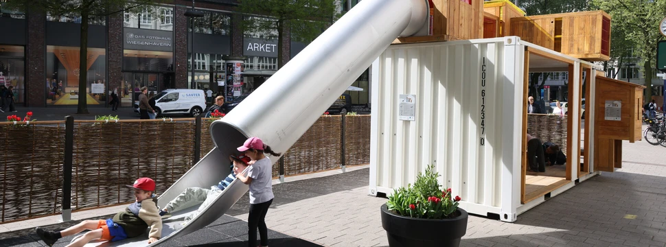 Hamburg hat jetzt einen Spielplatz mitten in der Innenstadt Auf einer Rutsche spielende Kinder an einem Spielcontainer