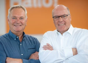 Zwei Männer mittleren Alters vor einer orangenen Wand