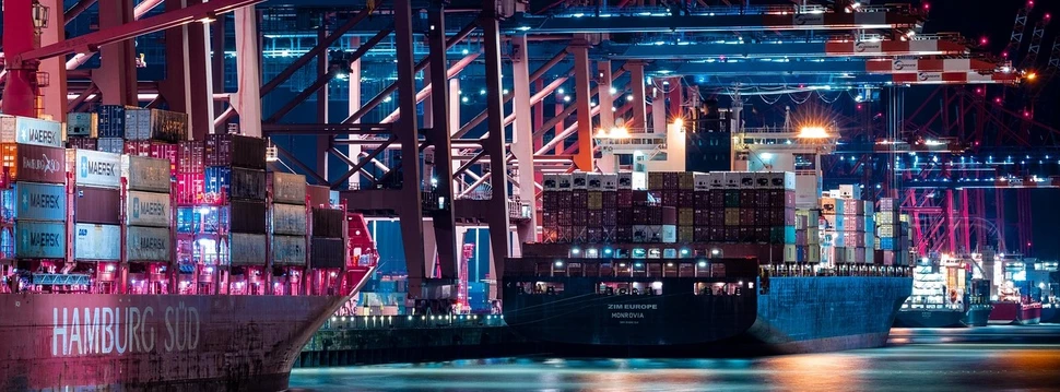 Hamburger Hafen bei Nacht Mehrere große Containerschiffe liegen nachts im Hamburger Hafen unter hell erleuchteten Ladebrücken.