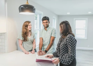 ein junges Paar besichtigt ein Haus mit einer Maklerin
