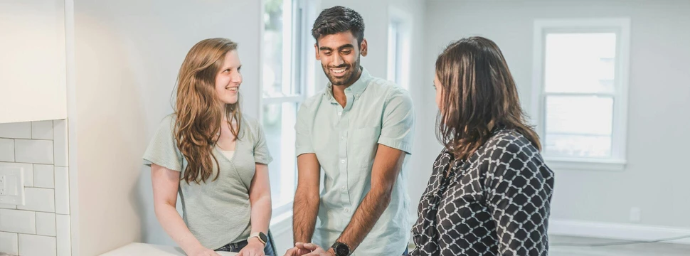 ein junges Paar besichtigt ein Haus mit einer Maklerin