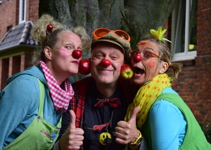 Drei lustige Clowns, die mit ihren Wangen Äpfel halten.