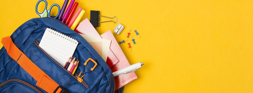 blauer Schulranzen gefüllt mit verschiedenen Schulmaterialien