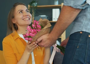 Eine Frau, die sitzend einen Blumenstrauß überreicht bekommt