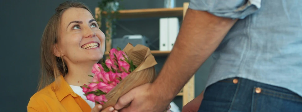 Eine Frau, die sitzend einen Blumenstrauß überreicht bekommt