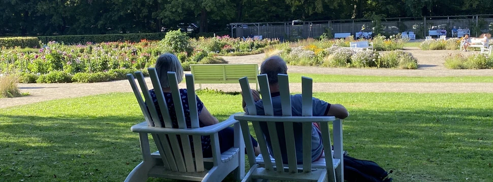Menschen sitzen auf zwei weißen Liegestühle im Dahliengarten